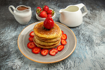 front view yummy pancakes with strawberries and honey on light background sweet fruit cake