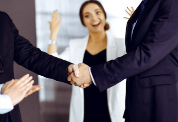 Unknown businesspeople are shaking their hands after signing a contract at meeting, close-up. Business communication concept