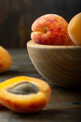 Fresh apricots in a wooden plate. Fruits are scattered on a wooden table.