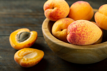 Fresh apricots in a wooden plate. Fruits are scattered on a wooden table.