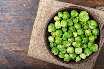 Fresh raw brussels sprouts in a bowl on a wooden table.
