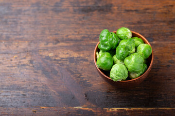 Bunch of fresh Bruxelles sprouts in a cup on wooden background.
