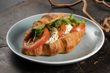 Fresh croissant with tomatoes, lettuce and mozzarella cheese. A classic breakfast of pastries, vegetables and cheese.