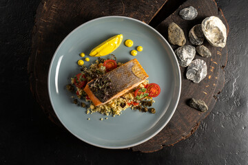 Grilled salmon garnished with couscous, cherry tomatoes, herbs and lemon sauce. A hot main course of fish and cereals.