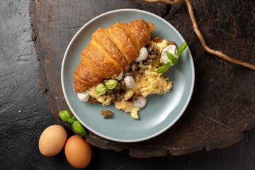Scramble egg croissant with truffle dressing and mushrooms. Classic hot breakfast with eggs and pastries.