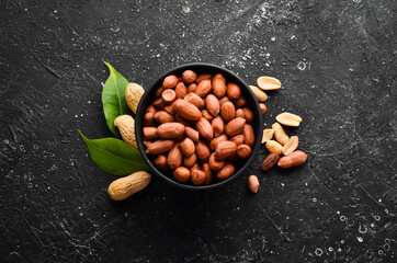 Peanuts in bowl on old table. Nut background. Top view.