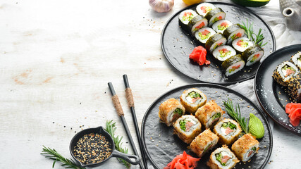 Set of traditional sushi on a black plate. Sushi and rolls on white wooden background.