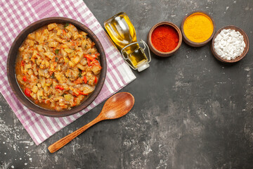 top view roasted eggplant salad in bowl oil wooden spoon different spices on dark background free space