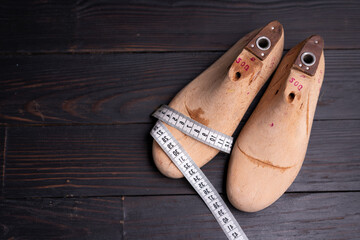Leather samples for shoes and wooden shoe last on dark wooden table.