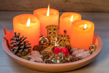 Festlicher Teller zum vierten Advent  mit brennenden Kerzen und Dekoration aus Kugeln, Gebäck, Sternen und Tannenzapfen