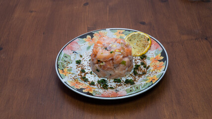 Delicious salmon tartare with chives and lemon on a wooden table