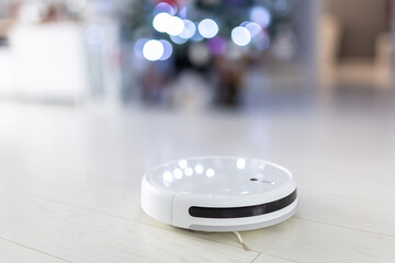 Robotic vacuum cleaner hoovering the floor at christmas tree