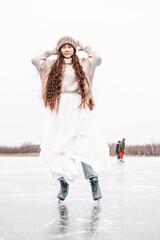 Fototapeta na wymiar Woman ice skating outdoors on a pond. Outdoors lifestyle portrait of girl in figured skates. Smiling and enjoying wintertime. Wearing stylish down sweater, skirt, knitted mittens. Ready for skating