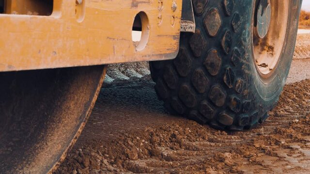 Close up shot of vibrating soil compacting roller machine at work.