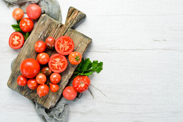Fresh red tomatoes on white wooden background. Greens. Top view. Free space for your text.