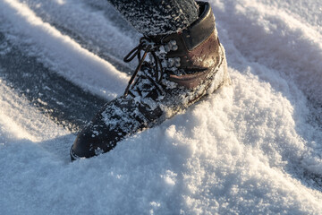 Woman lag in boot glides on ice covered with snow. Winter walking in warm and comfortable shoes...