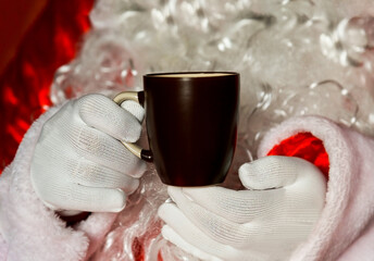 Fototapeta na wymiar Santa Claus is holding a black tea mug in the background. 