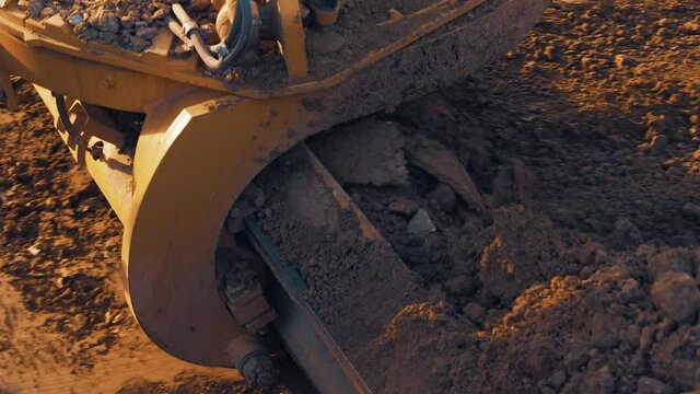 Slow motion close up shot of grader scoop moving soil.
