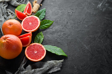 Fresh juicy grapefruit with leaves. Citrus fruits on black stone background. Top view. Free copy space.
