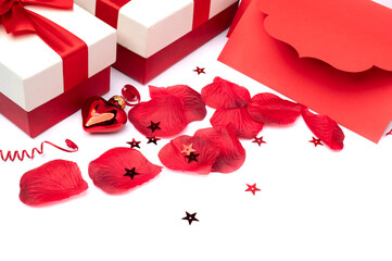 Gift boxes with bows as well as rose petals and a festive envelope on a white