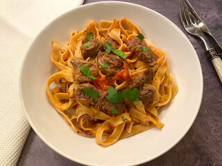 Beef strips, tagliatelle pasta and tomato sauce.