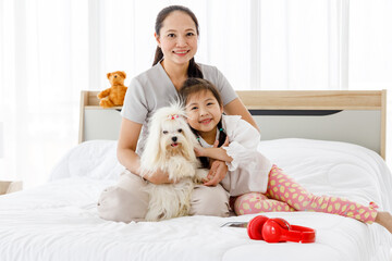 Obraz na płótnie Canvas Asian mother and daughter with Maltese in bedroom.