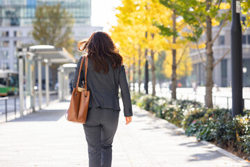 外を歩く働く女性の後ろ姿