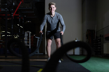 Young men working with ropes in the gym