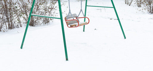 Empty kids swing with snow and nobody. Winter concept showing low traffic during cold winter