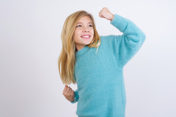 Attractive Cute Caucasian kid girl wearing blue knitted sweater against white wall celebrating a...