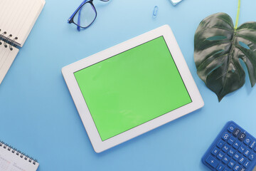 top view of digital tablet with office suppliers on blue background 
