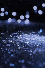 Glasscherben im Regen am Boden - Lichtreflektionen im Hintergrund - blau