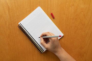 Taking notes in blank paper white notebook. graph, grid, black squared, woman hand and red pencil on wooden table background. new year's resolution, goals. 2021. coronavirus. copy space. 