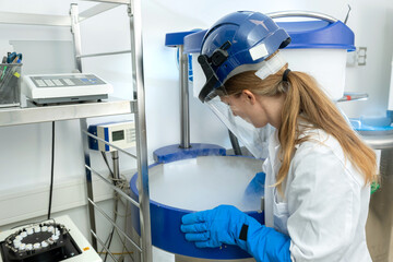 Kryokonservierung von Zellen und Gewebe im Stickstofflagertank, Biotechnologin öffnet Flüssigstickstoff Behälter. 