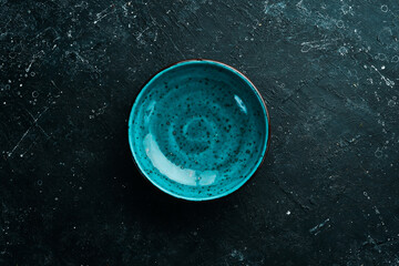 Turquoise plate on a black stone background. Top view. Rustic style.
