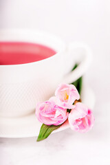 Raspberry tea and pink freesia flowers on a white background