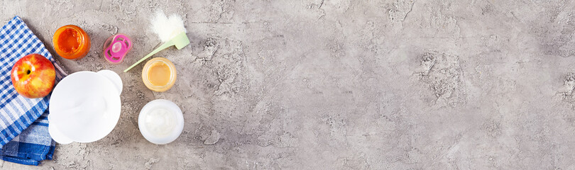 Bowl with vegetables puree and bottle of baby food on gray background. Top view