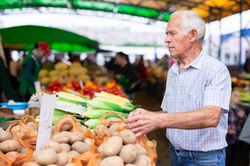european senior buying potatoes in market