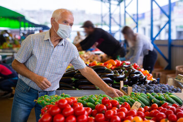 retired european man wearing medical mask protecting against virus buying tomatoes in market
