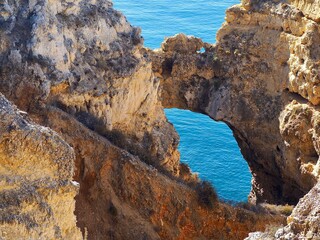 Fototapeta na wymiar The beauty of Portugal - hiking in Lagos in Portugal - a gate in the cliffs with view on the blue Atlanti ocean