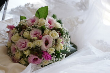 Close up of a Colorful wedding bouquet with a white dress background