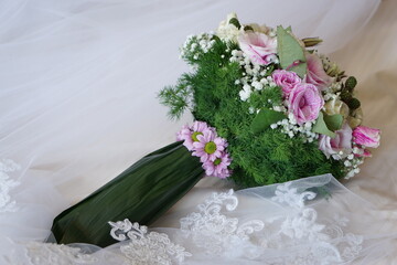 Close up of a Colorful wedding bouquet with a white dress background