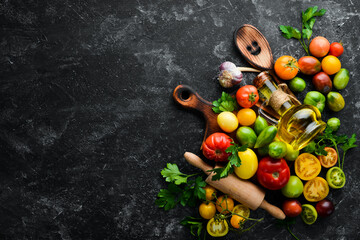 Vegetables. Fresh colored tomatoes On a black stone background. Top view. Free space for your text.