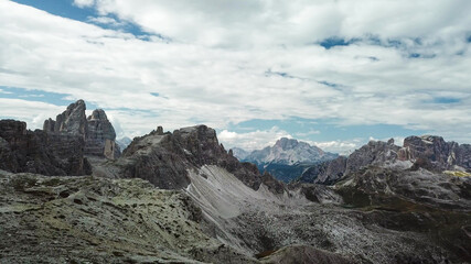A panoramic view on Italian Dolomites. There are many high and sharp peak in front, with many landslides. Dangerous climbing. Barely any plants growing in the  area. Raw and unspoiled landscape.