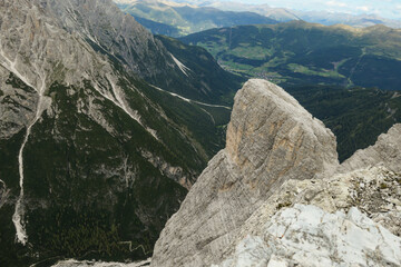 A panoramic view on a valley in Italian Dolomites. There is a massive mountain on the side, with...