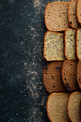 Fresh bread. Assortment of sliced black and white bread. Top view. Black stone background, rustic style.