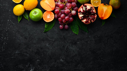Fruits. Seasonal and tropical fruits on a black stone background. Food background. Top view. Free space for your text.