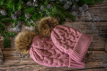 Obraz na płótnie Canvas Warm knitted pink hats with pompom for mother and daughter. Christmas decoration on wooden background.