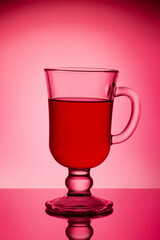 Glass with mulled wine on a red background. Glass for light.