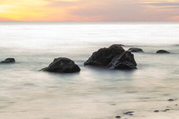 Fototapeta na wymiar Beautiful sunset over Baltic sea with stones in the water, long exposure photography.